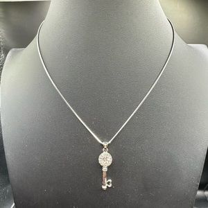 Key with heat tip and clear crystals on a silver chain.